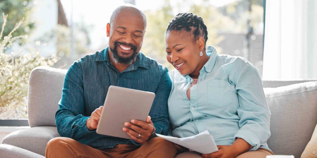 a mature couple looking through their bills while using a digital tablet.