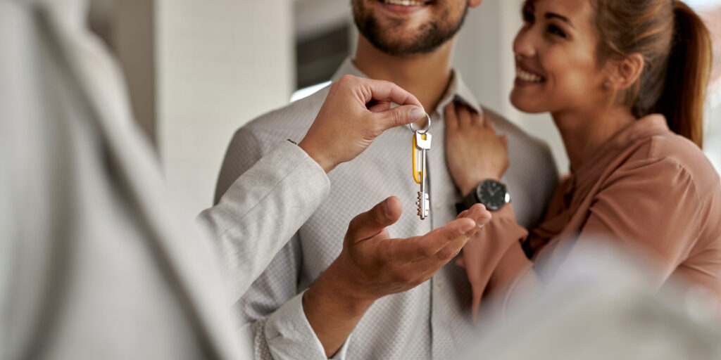 Close-up of couple receiving keys of their new home from real estate agent.