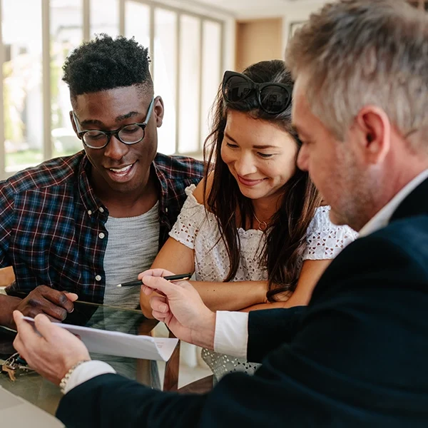 187317467 Young couple sitting with real estate agent reviewing paperwork.