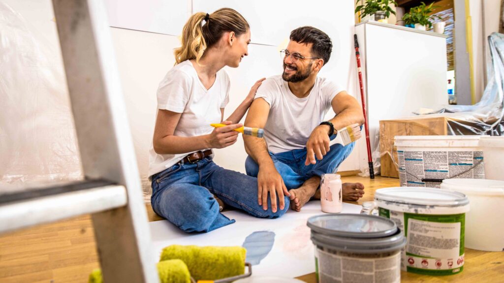 Young couple sitting on the floor choosing color for painting th