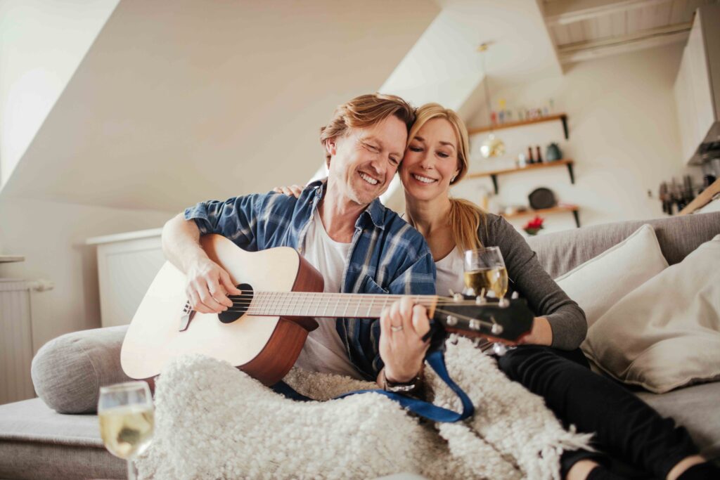 Middle aged Caucasian couple playing the guitar the living room