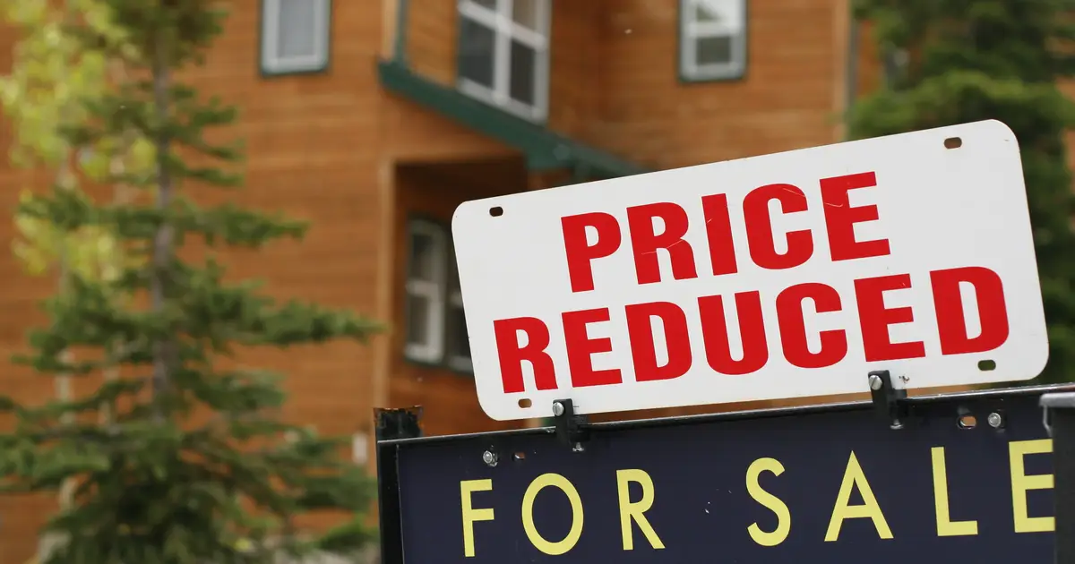 "For Sale" sign with "Price Reduced" in front of house