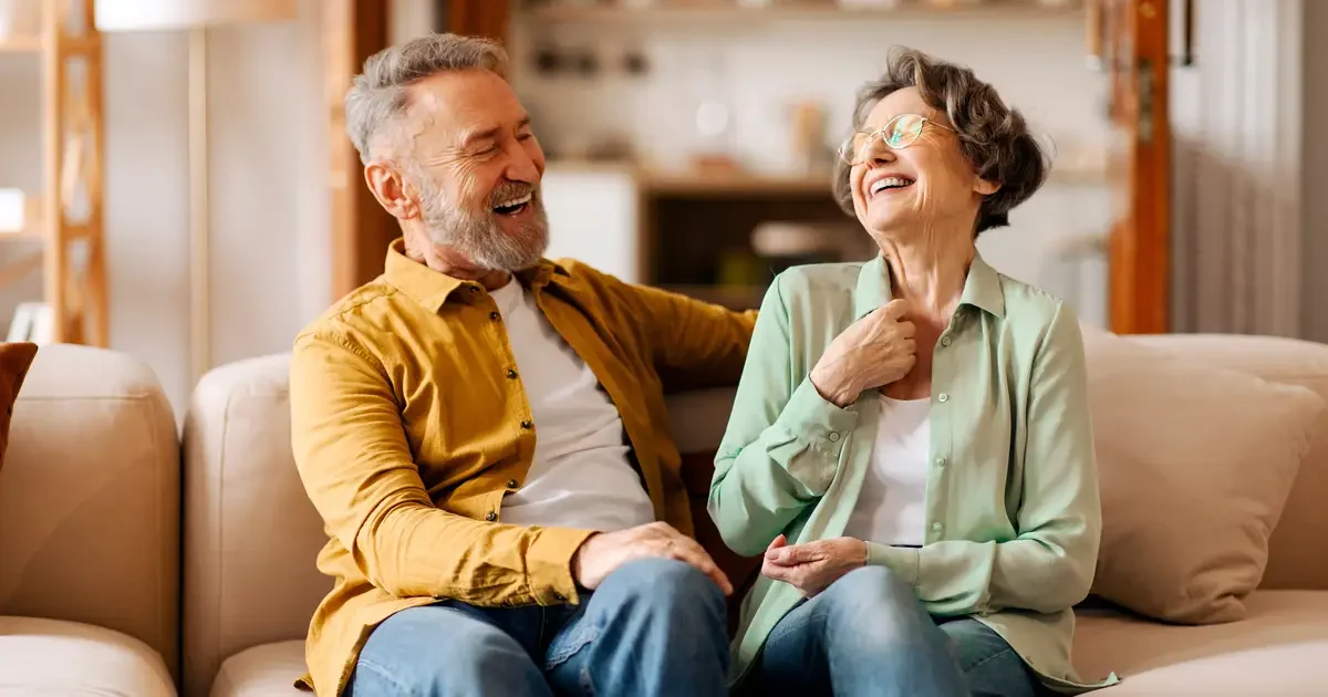 Retired couple laughing on the couch