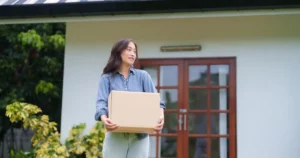 Young woman with box in front of house