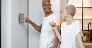 Smiling couple adjusting thermostat