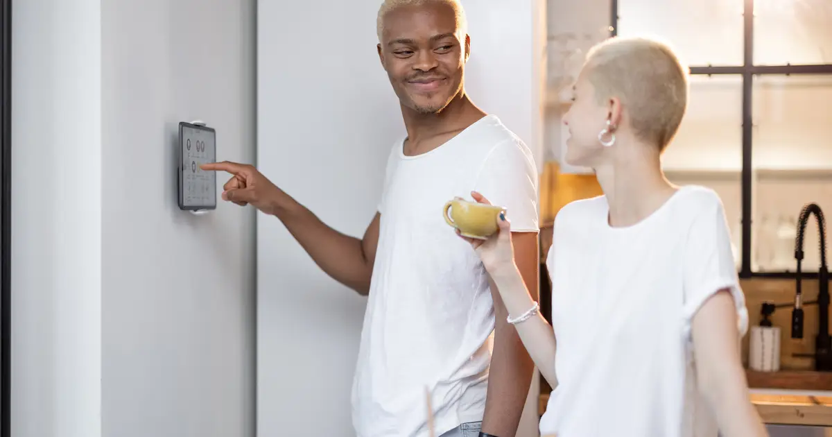 Smiling couple adjusting thermostat