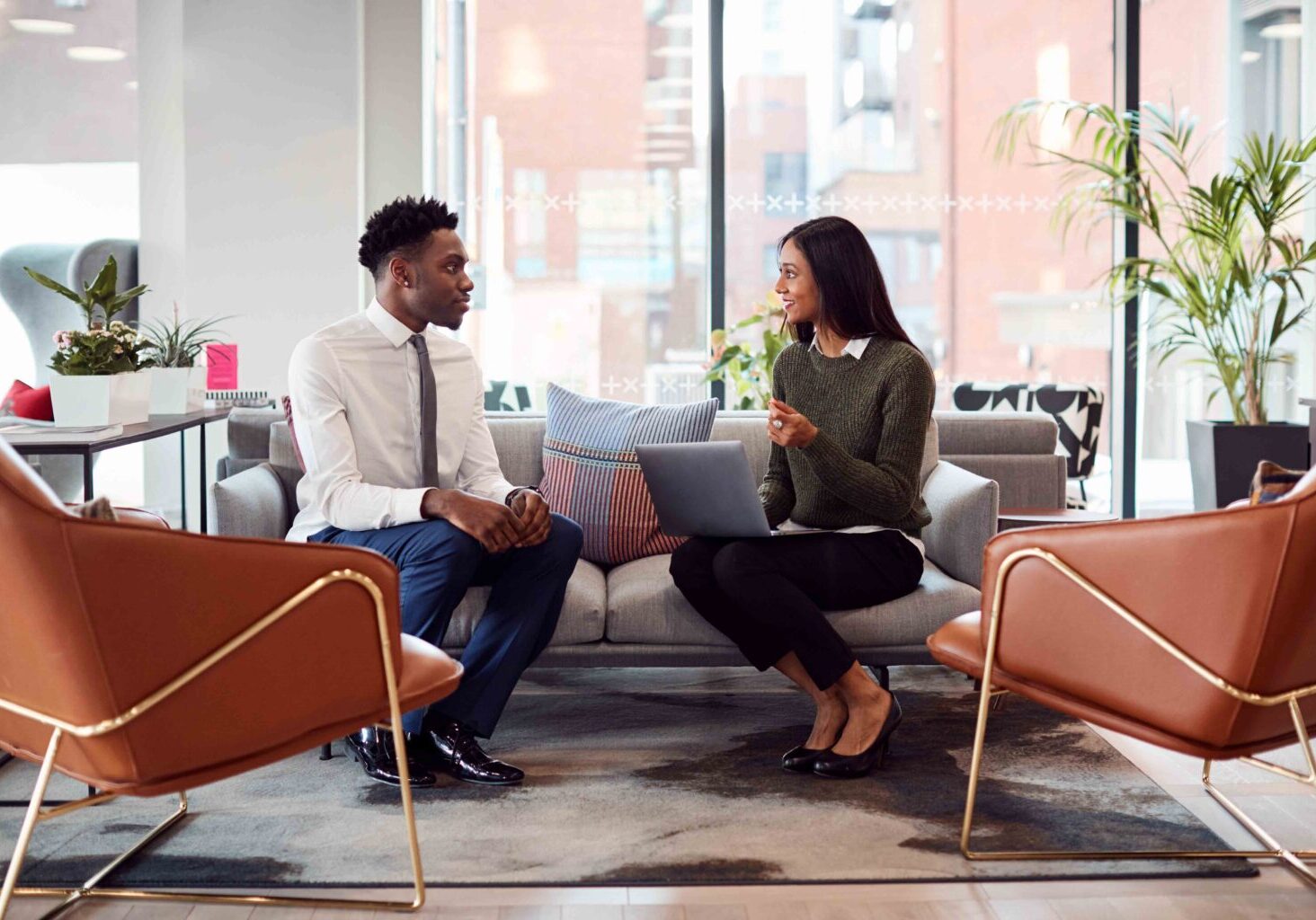 Businesswoman Interviewing Male Job Candidate In Seating Area Of Modern Office